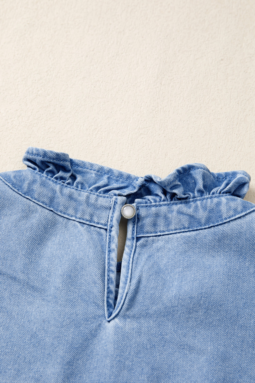 Women's distressed denim top by Trendsi with frilled collar and flutter sleeves, featuring a casual, trendy design.