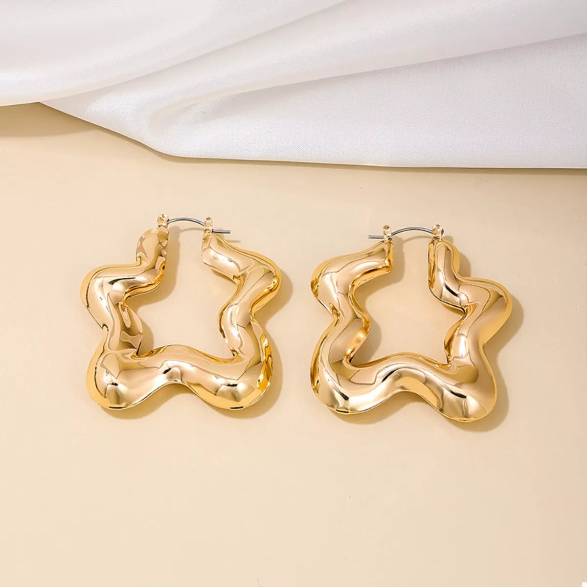 Star-shaped hoop earrings in gold-tone metal, stylish fashion jewelry with a celestial star design, perfect for trendy accessories.