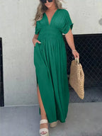 Plus size full-length maxi dress with slit, V-neck, and smocked waist by Trendsi, featuring flowing fabric and elegant design.