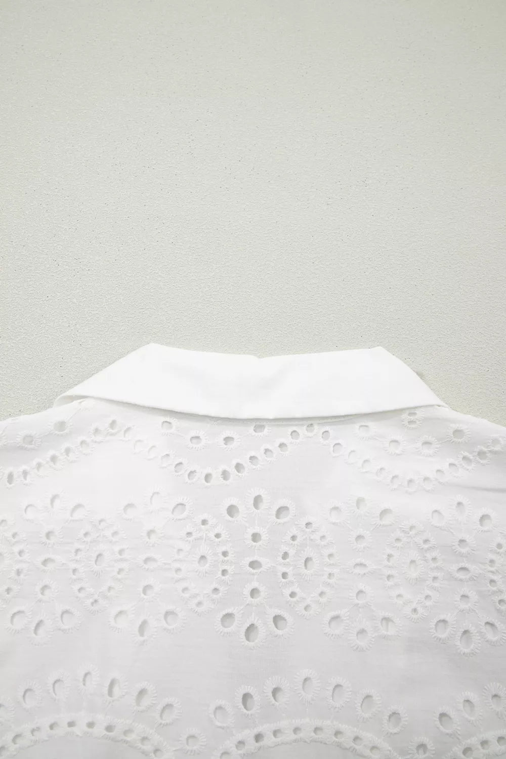 Solid color eyelet embroidered T-shirt mini dress by Trendsi, featuring eyelet details and soft fabric, shown on a model.