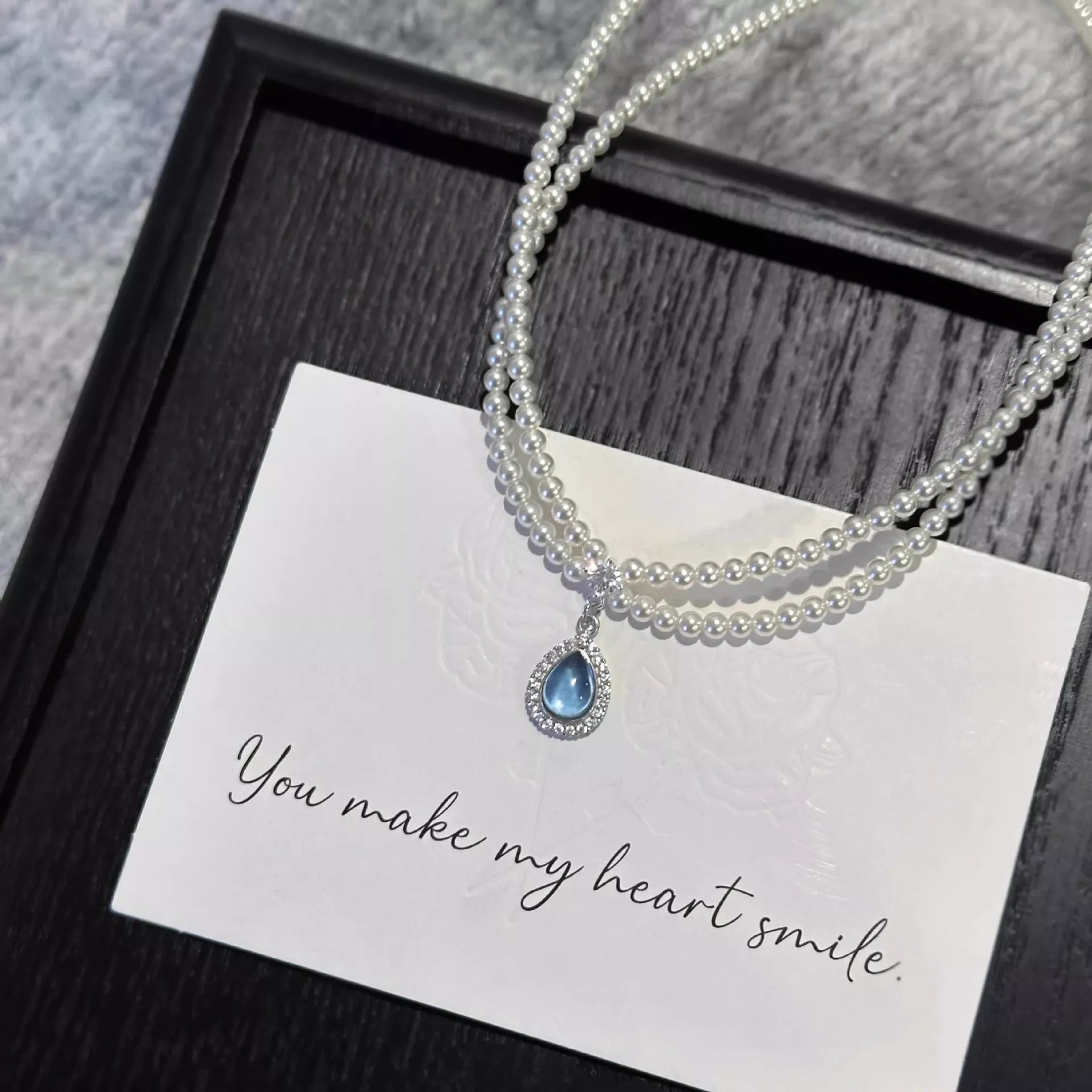 Double layered pearl necklace with teardrop pendant from Shopimist, featuring elegant white pearls and a delicate teardrop charm.