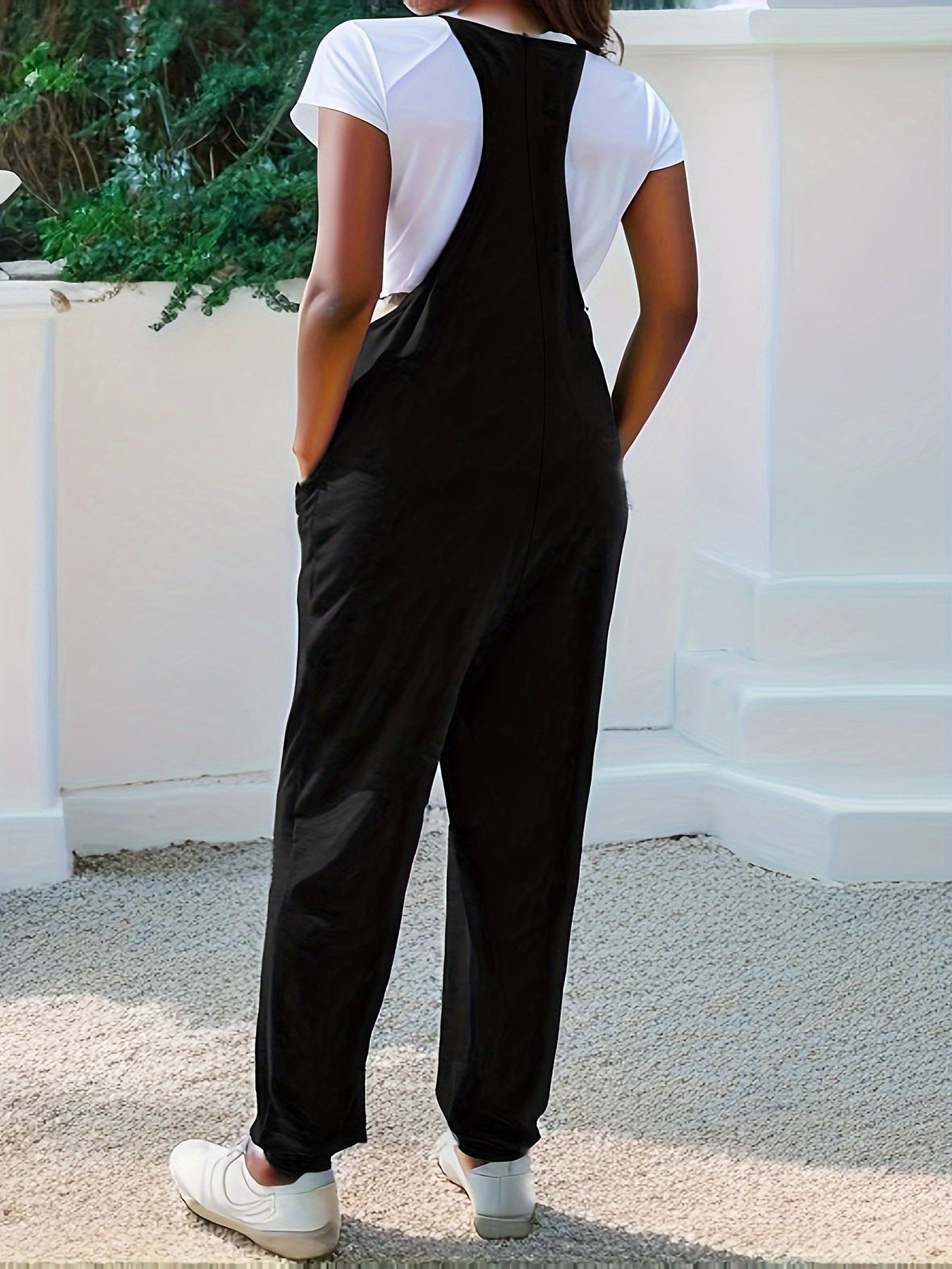 Casual loose-fit spaghetti strap jumpsuit with pockets by Trendsi, shown in a relaxed fit with adjustable straps and side pockets.