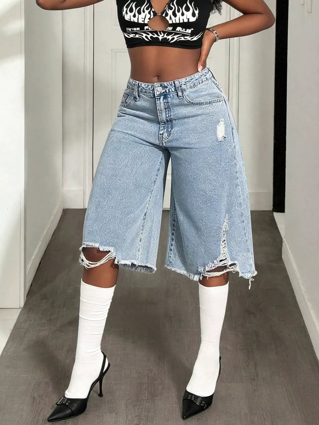 Distressed wide-leg denim shorts by Shopimist, featuring frayed edges and a relaxed fit, displayed on a hanger.
