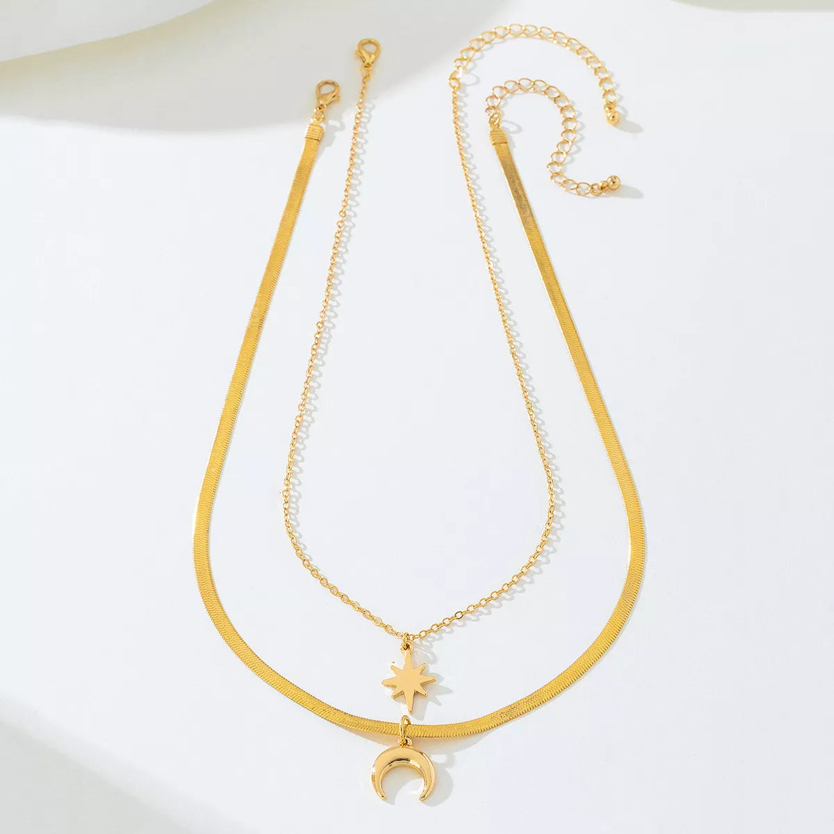 Gold-plated moon and star necklace set featuring two delicate pendants, perfect for layered jewelry styles.