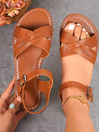 Women's crisscross ankle strap flat sandals in premium faux leather with buckle detail, stylish and comfortable shoe from Trendsi.