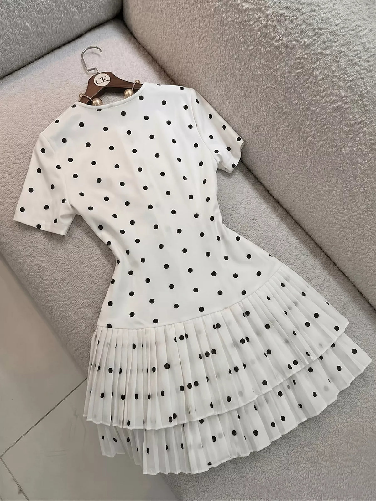 Polka dot pleated hem mini dress from Trendsi, featuring a stylish design with a fitted bodice and flowing skirt.