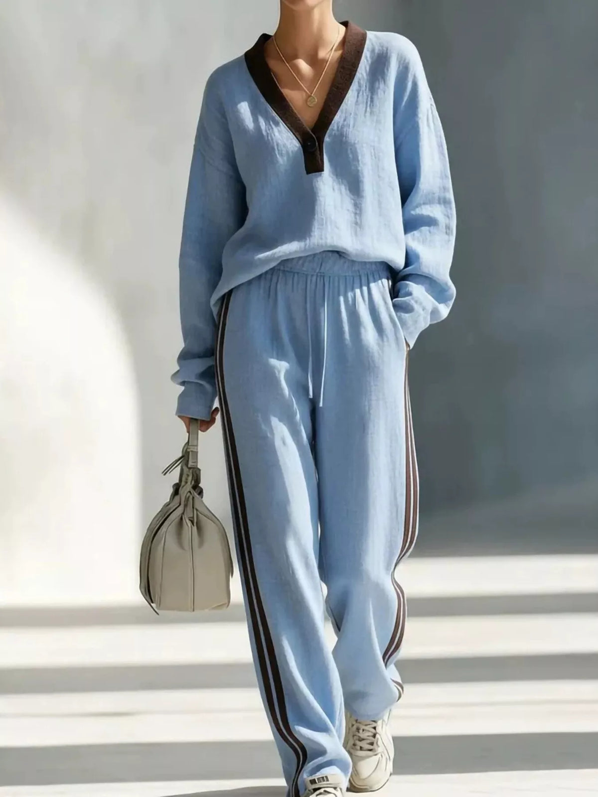Women's contrast V-neck top and striped pants set by Trendsi, featuring a stylish V-neck top and coordinating striped pants.