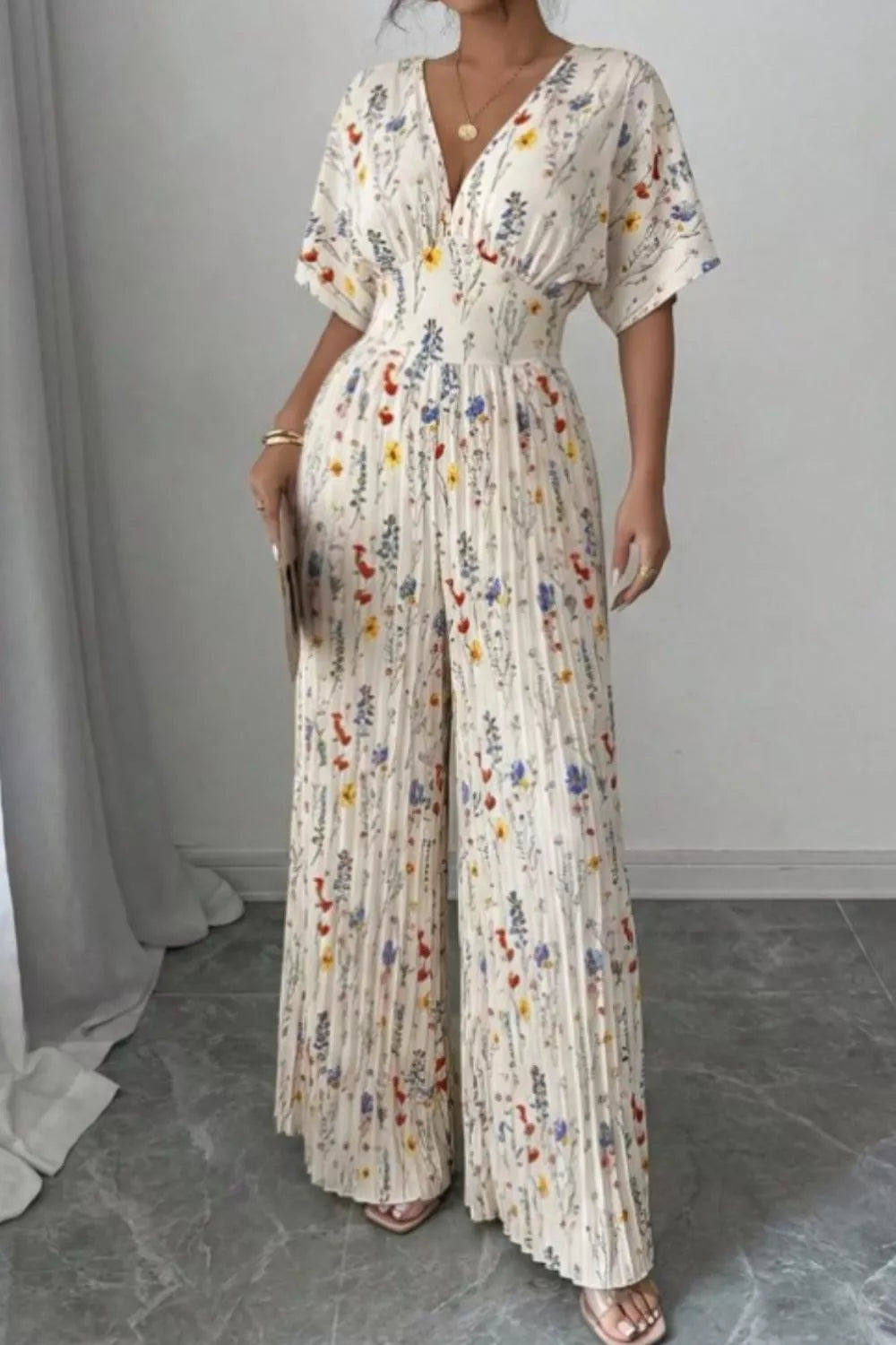 Floral print wide-leg pleated jumpsuit from Trendsi, featuring a flowing design and stylish pattern, shown on a model.
