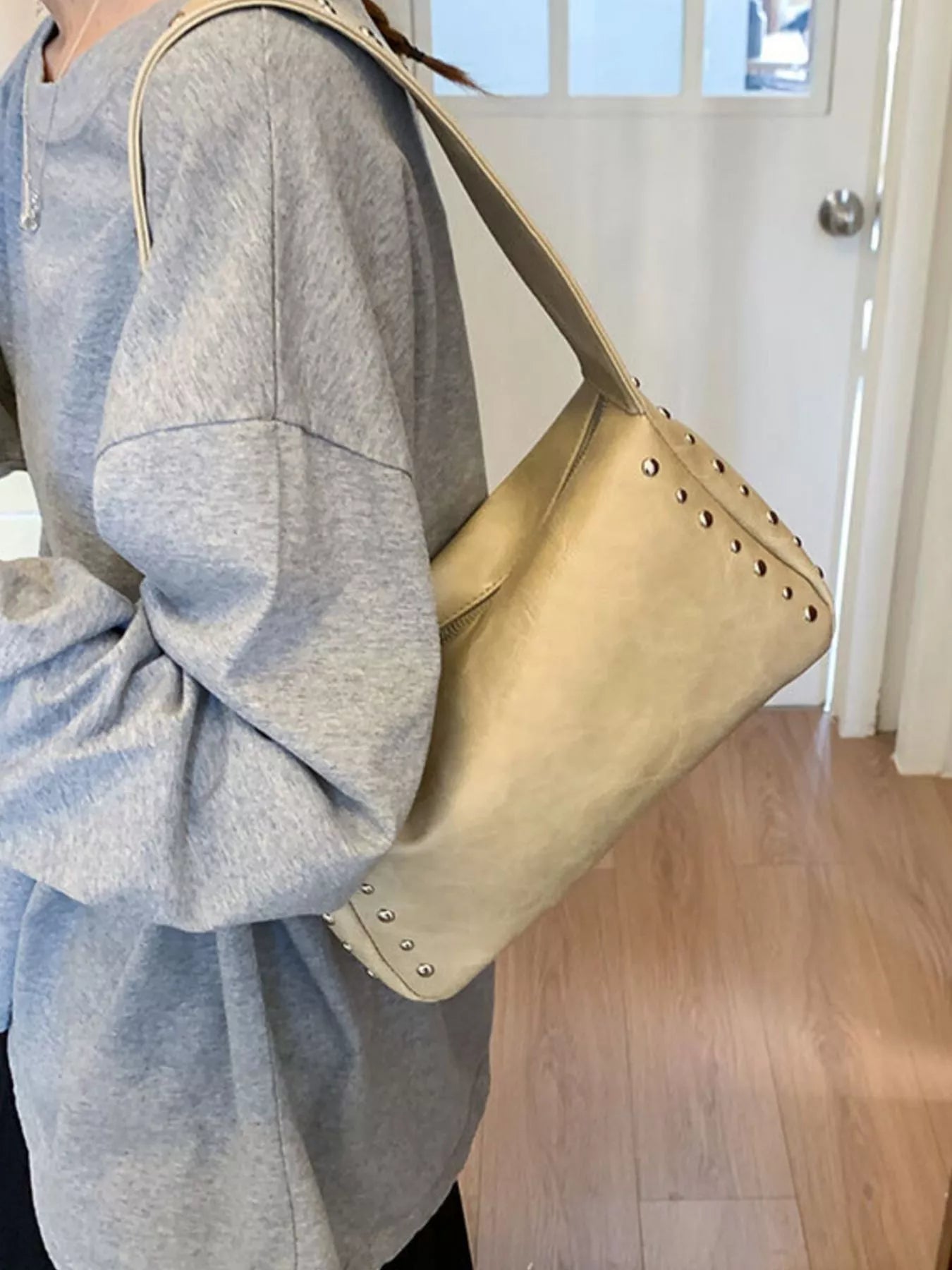 Black plush fashion hub shoulder bag with studded accents, featuring a sleek design and adjustable strap for everyday use.