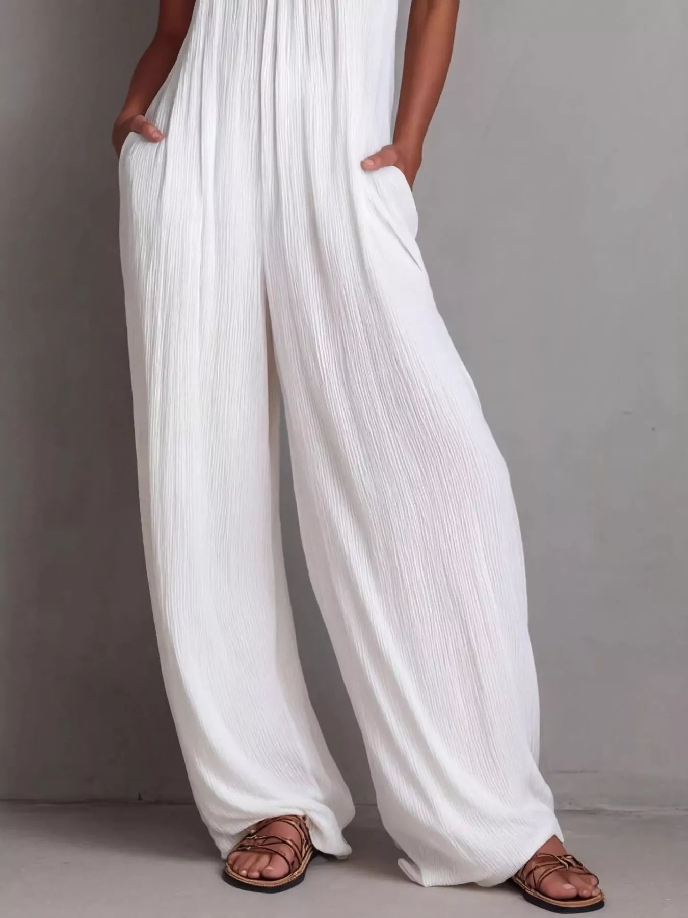 Plush Fashion Hub sleeveless wide-leg jumpsuit in black with a relaxed fit and deep V-neck, displayed on a hanger.