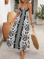 Women's printed halter neck maxi dress with tie-back detail by Plush Fashion Hub, featuring vibrant floral patterns and flowing fabric.