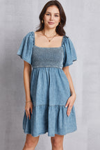 VYSN smocked square neck mini denim dress displayed on a hanger, showcasing a stylish sleeveless design with a fitted waist.