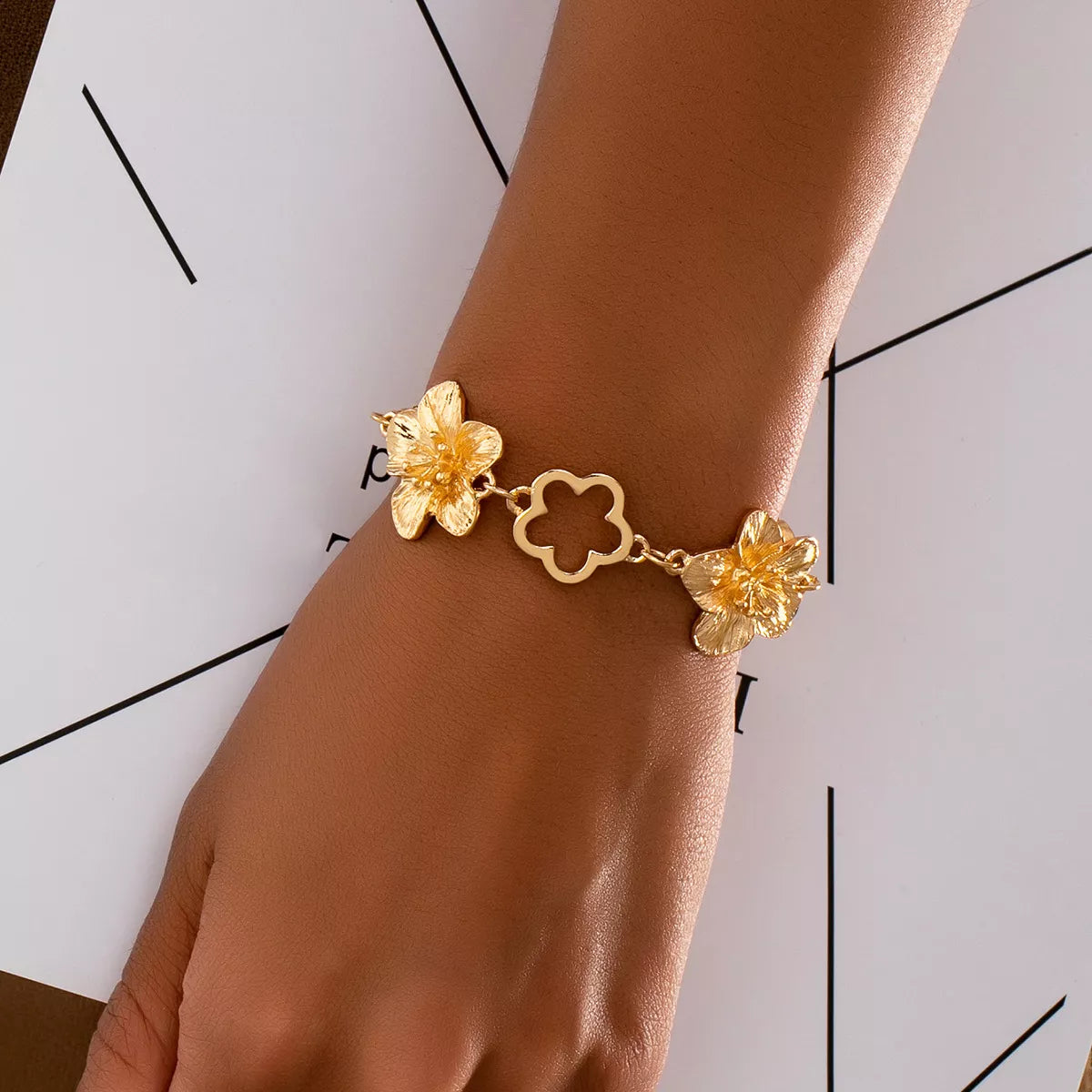 18K gold-plated flower bracelet with delicate floral design and adjustable chain, featuring shiny gold finish.