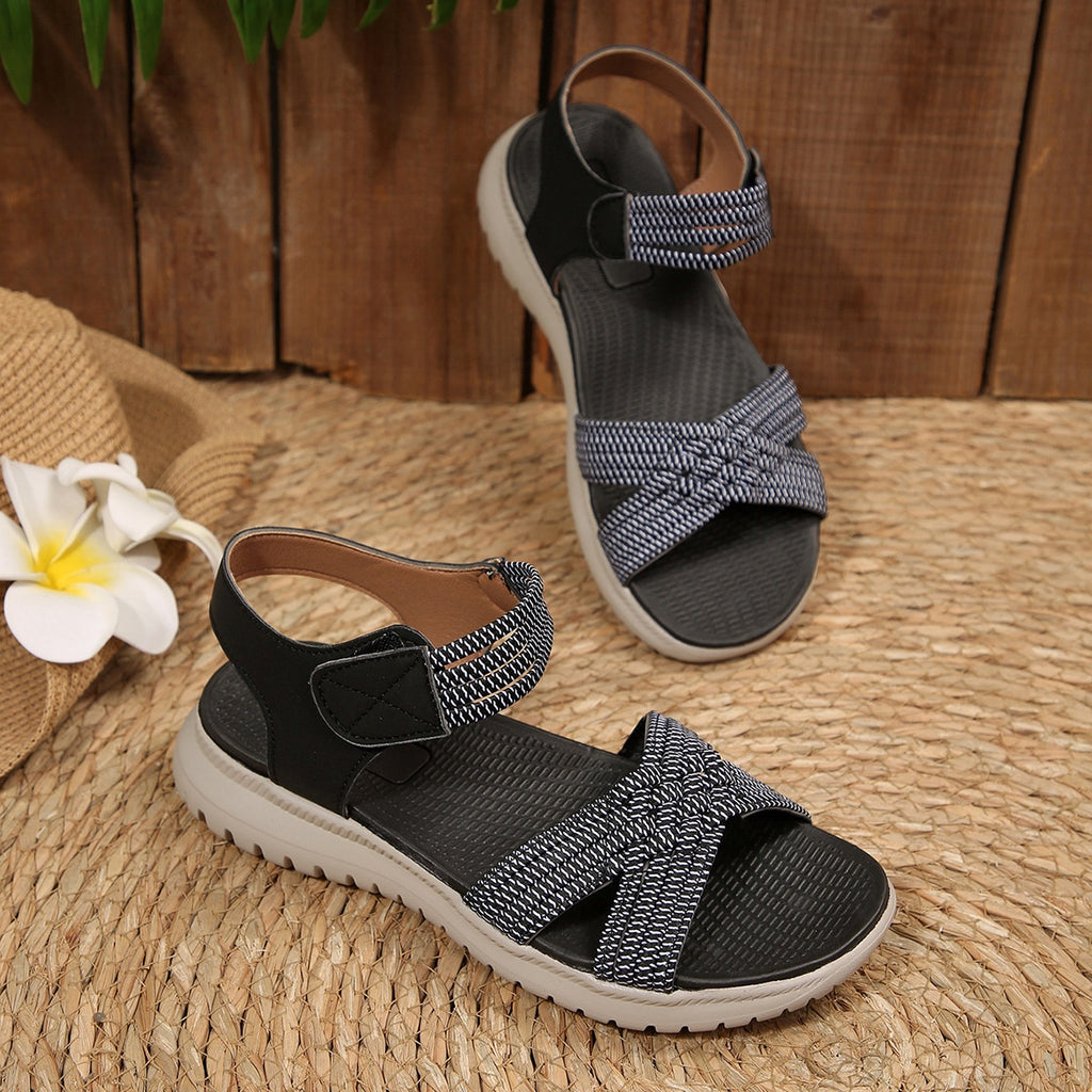 Women's open toe woven strap flat sandals made of faux leather, featuring comfortable slide design and stylish detail.