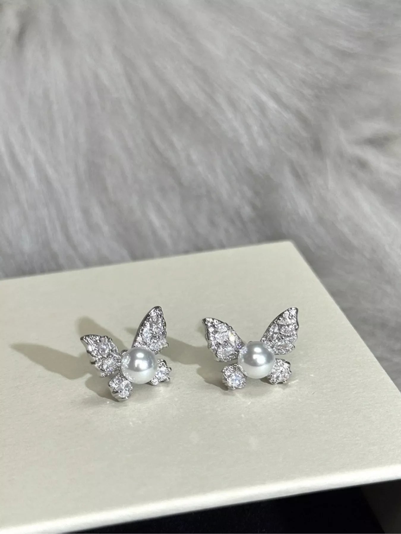 Silver butterfly pearl stud earrings from Plush Fashion Hub featuring elegant pearl accents and butterfly-shaped design.