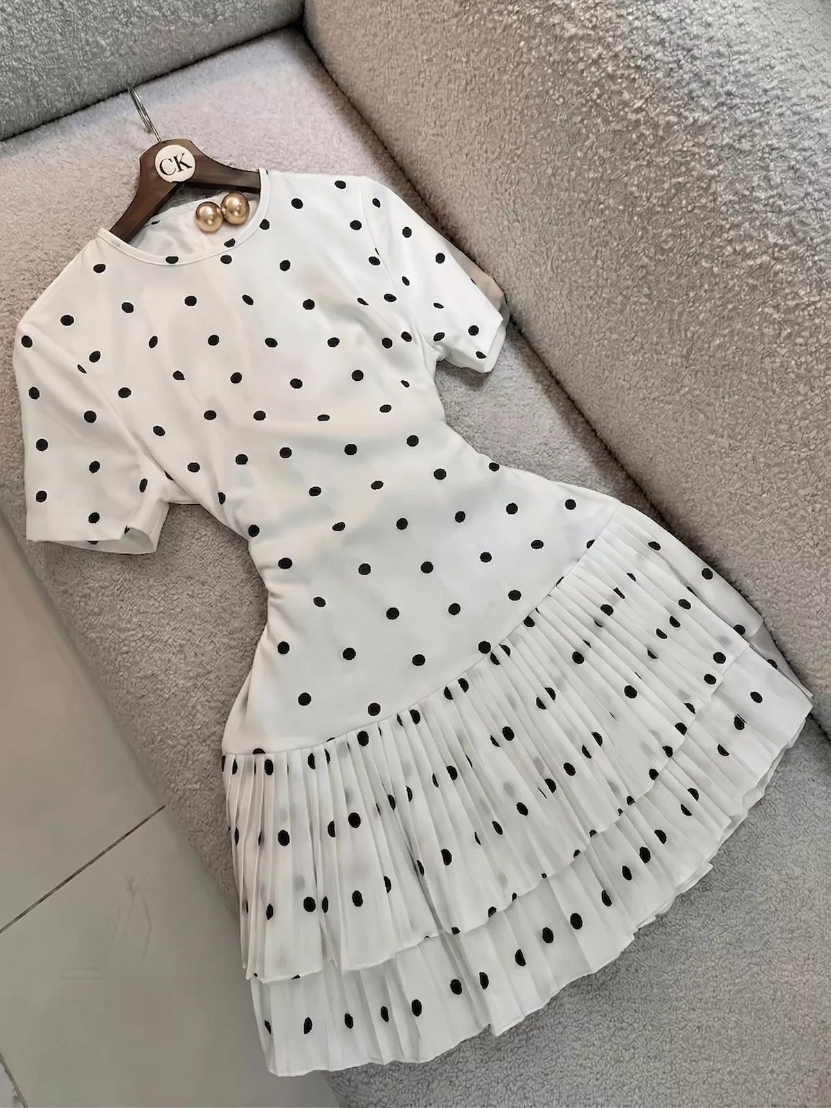 Polka dot pleated hem mini dress by Trendsi, featuring a stylish design with a flowy pleated skirt and classic polka dot pattern.