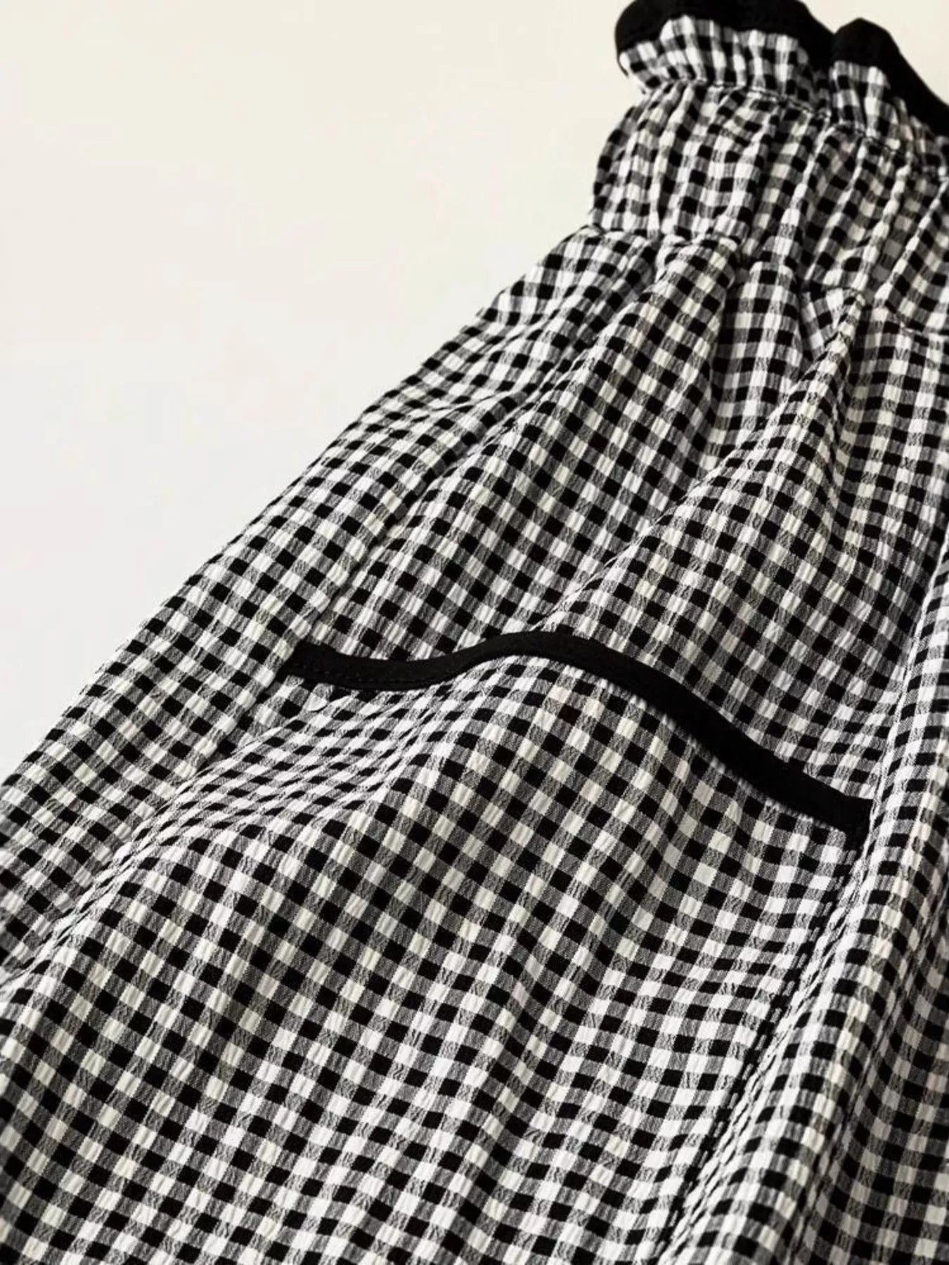 Women's high-waisted gingham wide-leg pants with pockets, stylish trendy pants from Trendsi, shown in black and white checkered pattern.