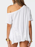 Women's off-shoulder asymmetrical flowy T-shirt by Trendsi, featuring a stylish, loose fit with a unique hem design.