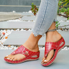 Women's faux leather wedge sandals with toe post and mid-heel, featuring a stylish design and comfortable fit.