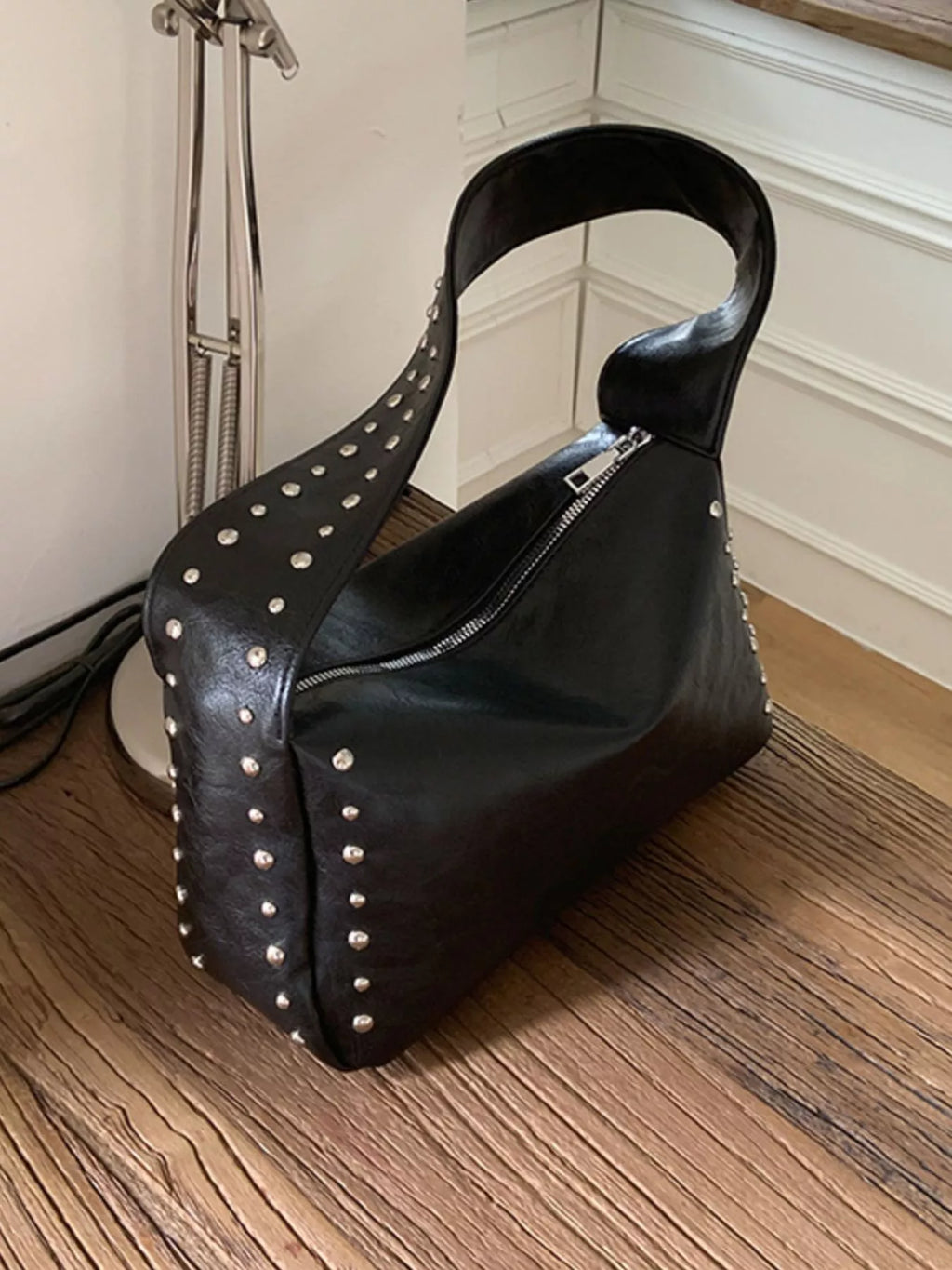 Black shoulder bag with studded accents, featuring a sleek design and a top handle, by Shopimist.
