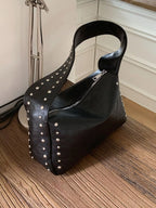 Black shoulder bag with studded accents, featuring a sleek design and a top handle, by Shopimist.