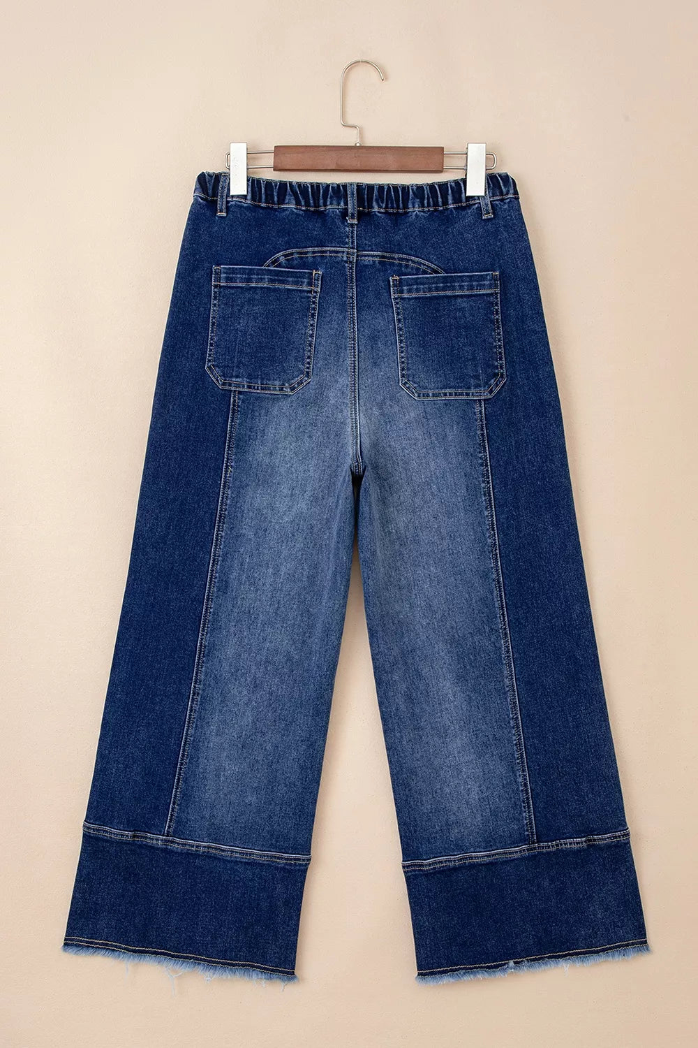 Wide-leg denim pants with drawstring, seam detail, and raw hem from Plush Fashion Hub, shown on a hanger.