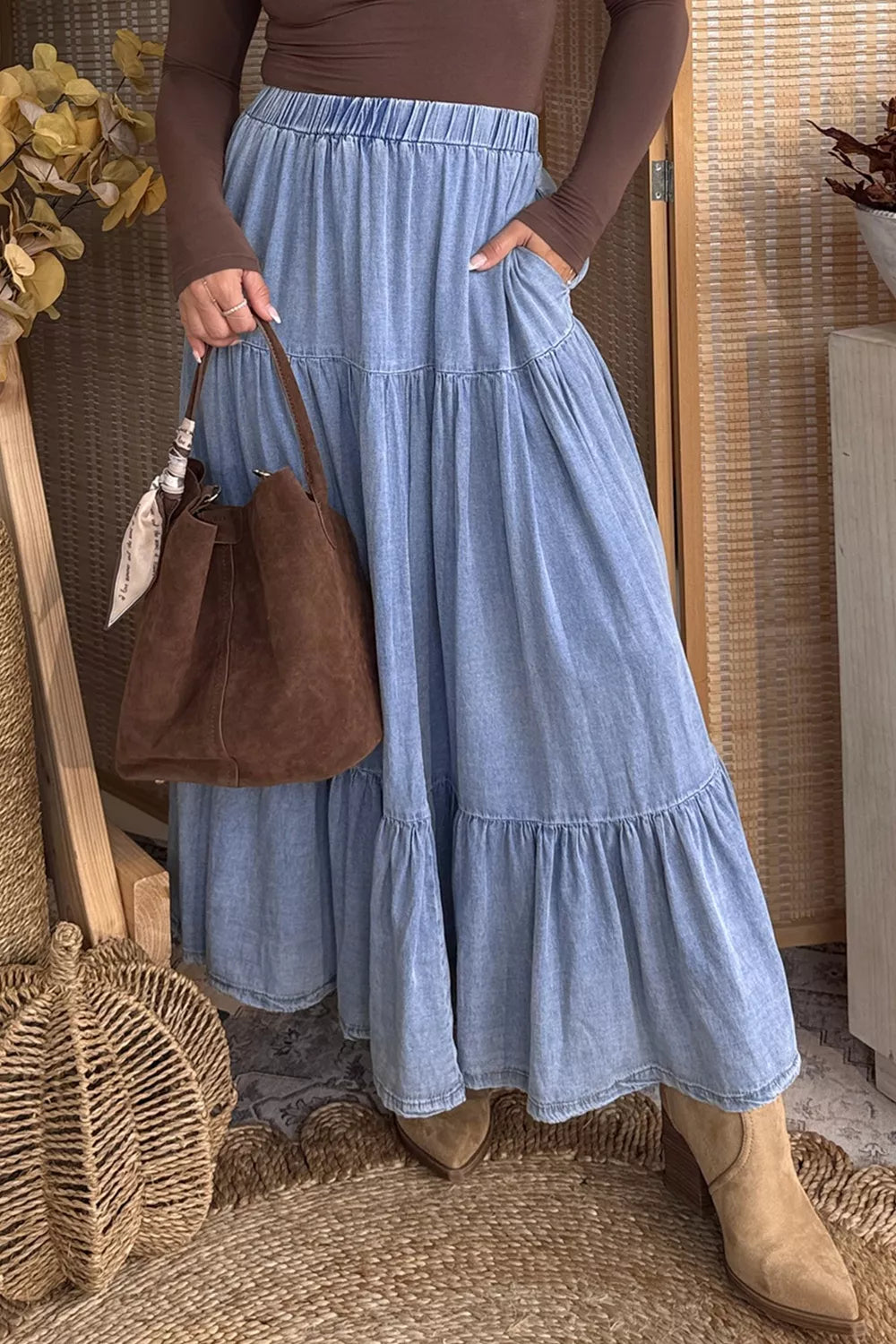 Flowing denim maxi skirt with elastic waist, ruffled tiers, and flared design by Plush Fashion Hub, shown on a model.