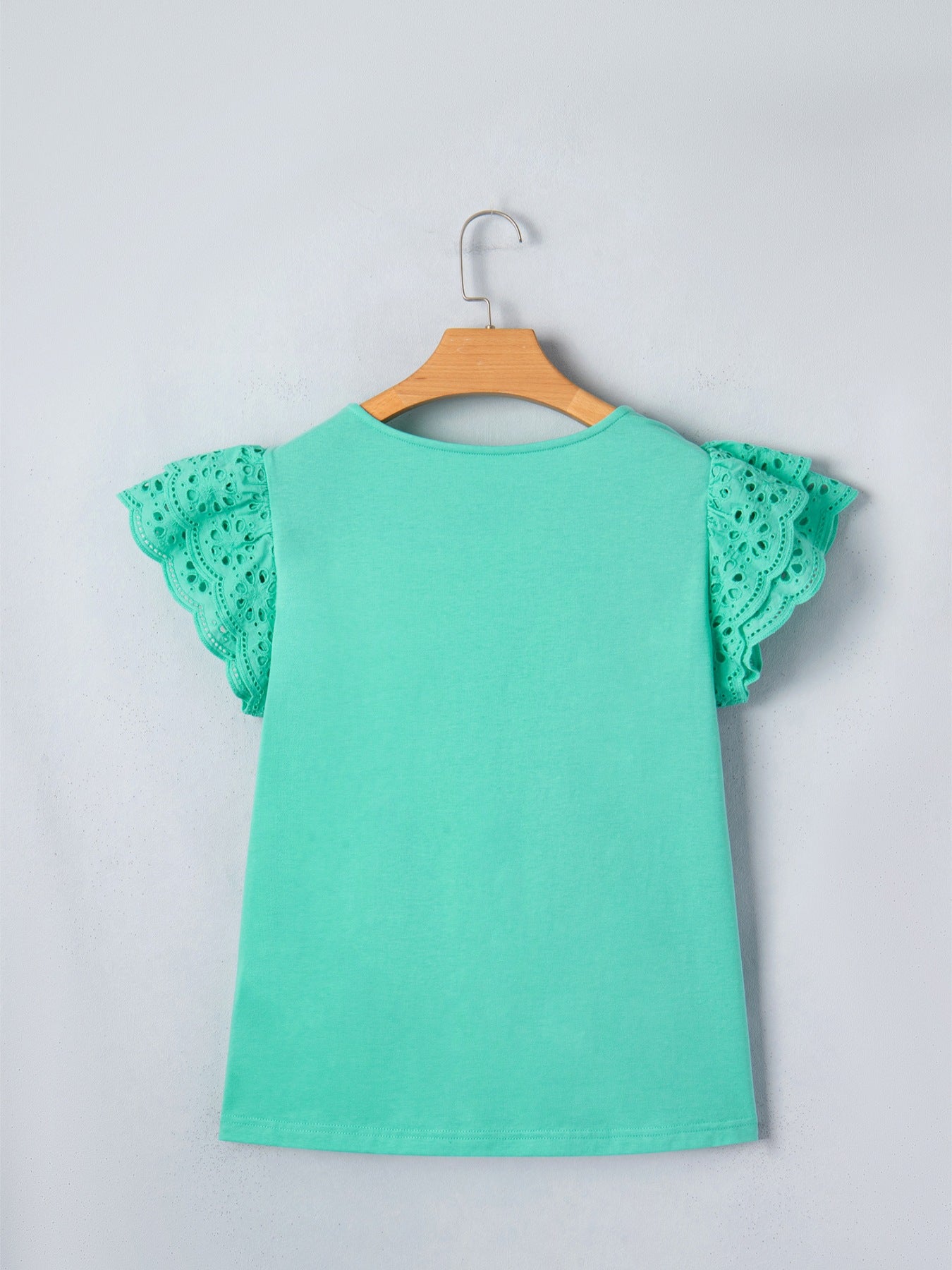 Ruffled eyelet lace cap sleeve top with cutout detail, stylish and feminine blouse from Trendsi, featuring delicate lace and ruffled accents.