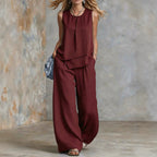 Women's sleeveless two-piece set from FitiqueFit with solid color wide-leg pants and matching top, shown in a casual indoor setting.