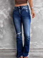 Distressed flare denim jeans from Plush Fashion Shop featuring ripped details and a high-waist fit on model.