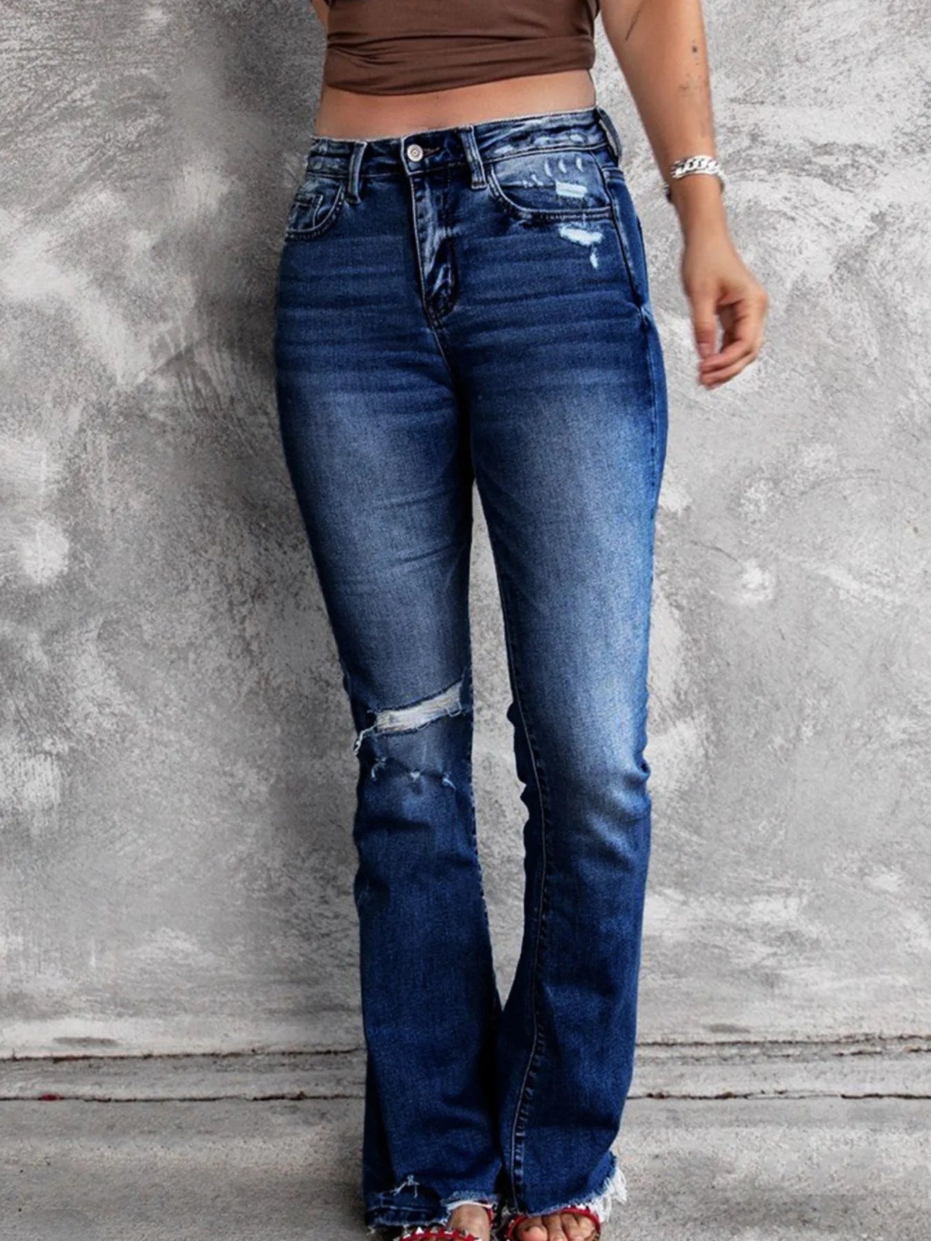 Distressed flare denim jeans from Plush Fashion Shop featuring ripped details and a high-waist fit on model.
