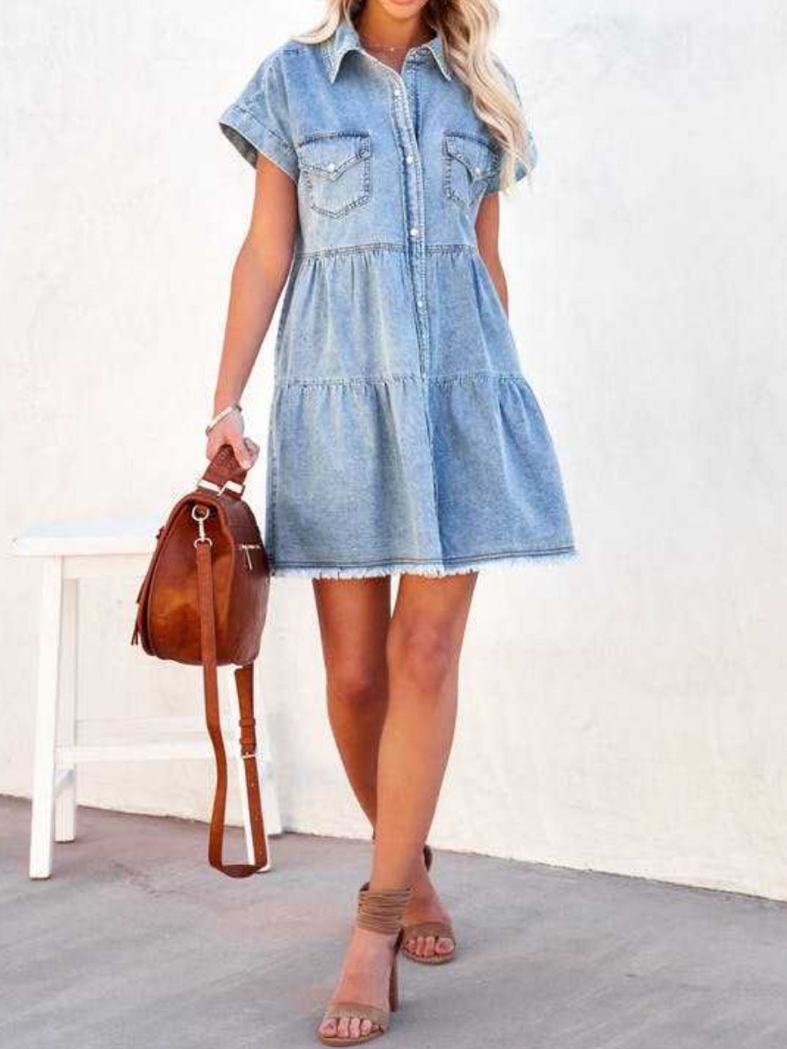 VYSN raw hem short sleeve denim dress hanging on a wooden background, showcasing casual fashion and distressed denim style.