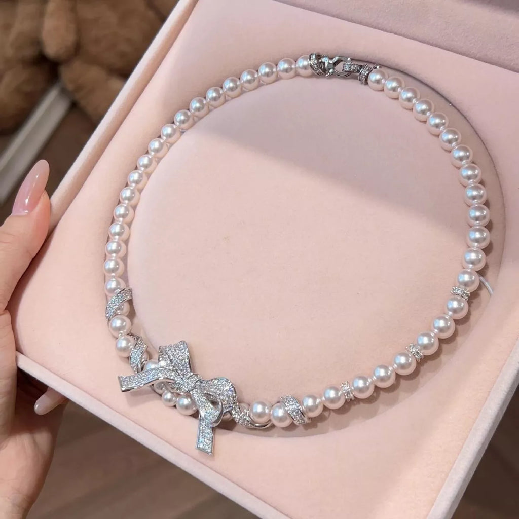Pearl necklace with a bow pendant, elegant jewelry piece featuring white pearls and a delicate bow charm.