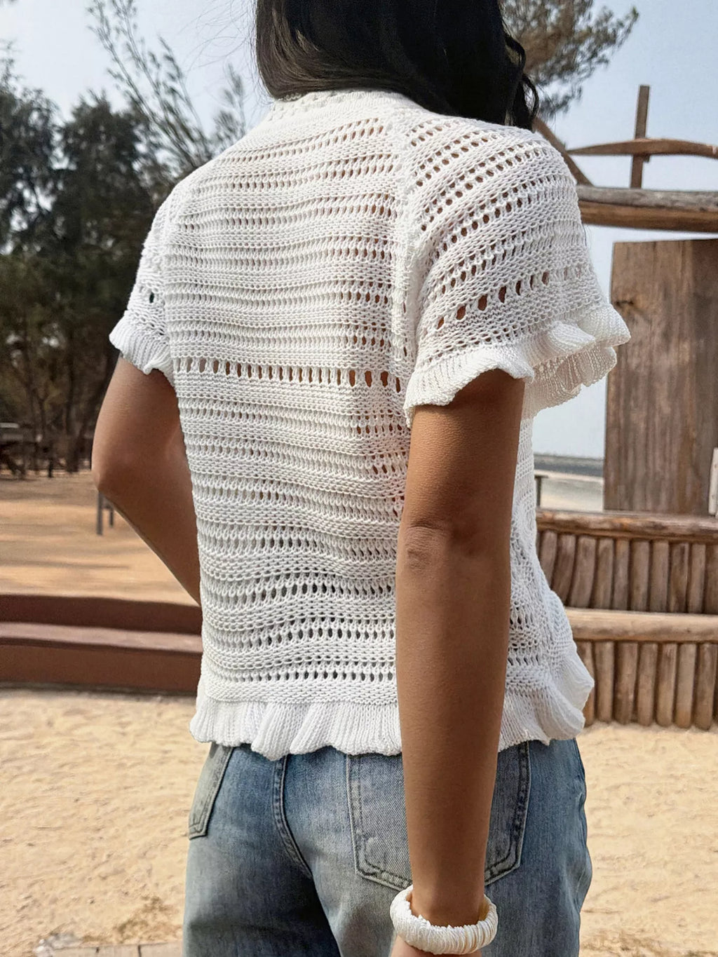 Openwork ruffled hem knit top by Trendsi, featuring a stylish openwork design and ruffled hem, perfect for casual or chic outfits.