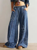 Wide leg jeans by Shopimist with floral appliques, featuring a relaxed fit and decorative flower details on the denim.
