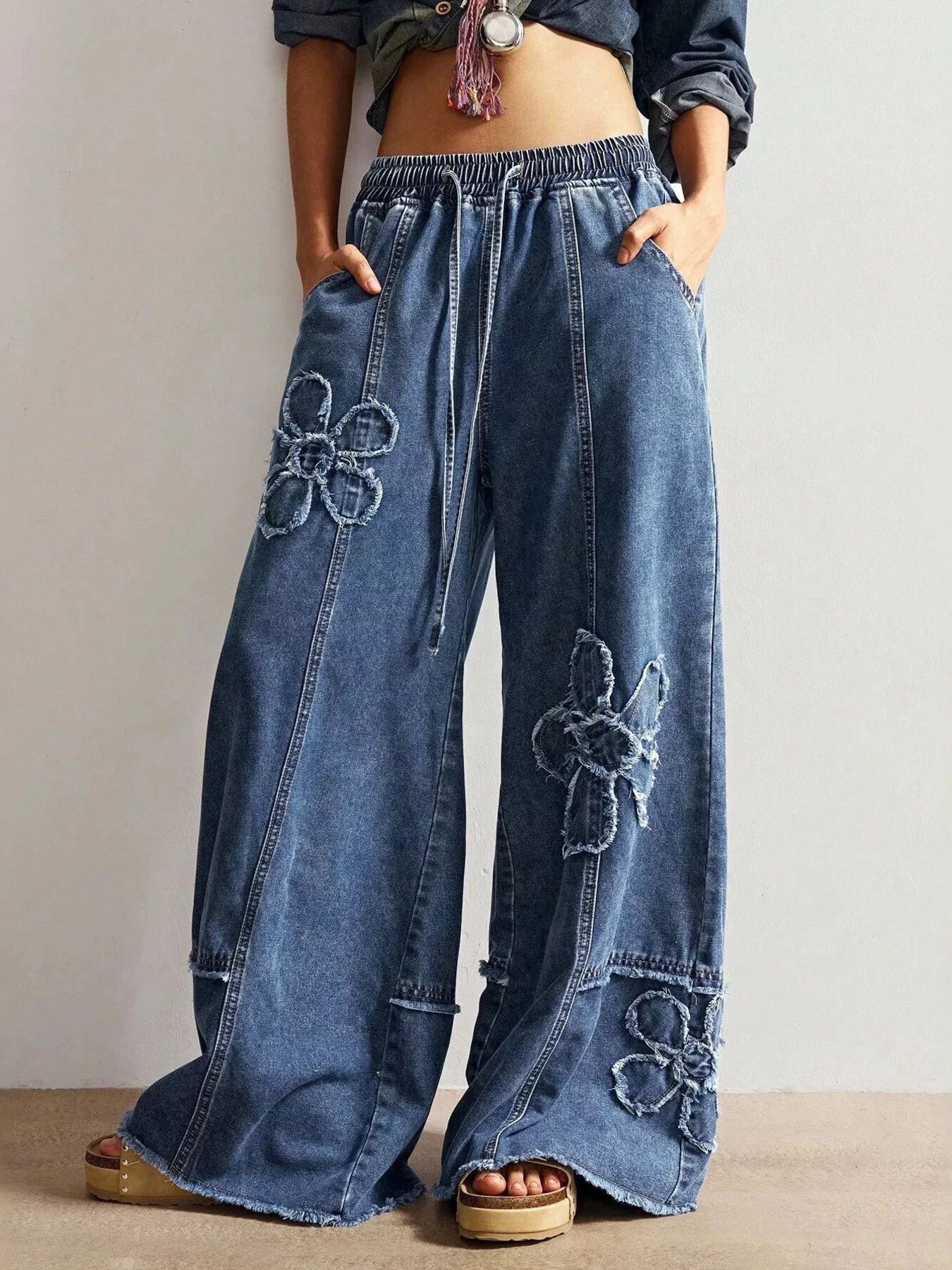 Wide leg jeans by Shopimist with floral appliques, featuring a relaxed fit and decorative flower details on the denim.