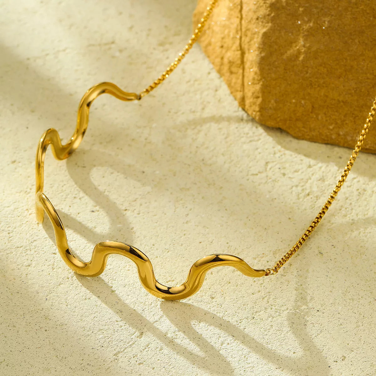 18K gold-plated wave necklace with sleek, flowing design, featuring a shiny, polished surface and elegant chain display.