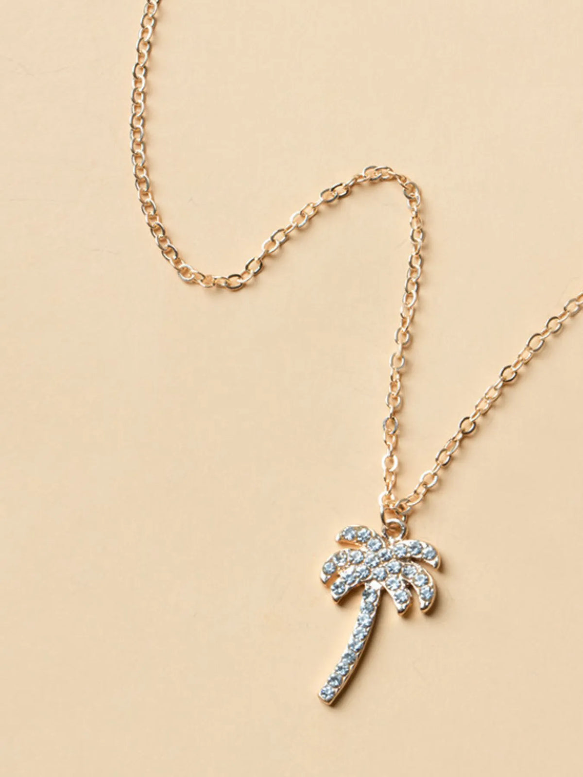 Zircon palm tree pendant necklace with sparkling stones, jewelry piece from Plush Fashion Hub, on a chain against a neutral background.