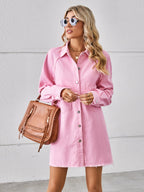 VYSN raw hem button-up denim dress hanging on a rack, showcasing casual fashion with a distressed hem detail.