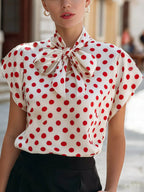 Polka dot tie neck blouse by Shopimist featuring long sleeves and a classic pattern, stylishly displayed on a hanger.