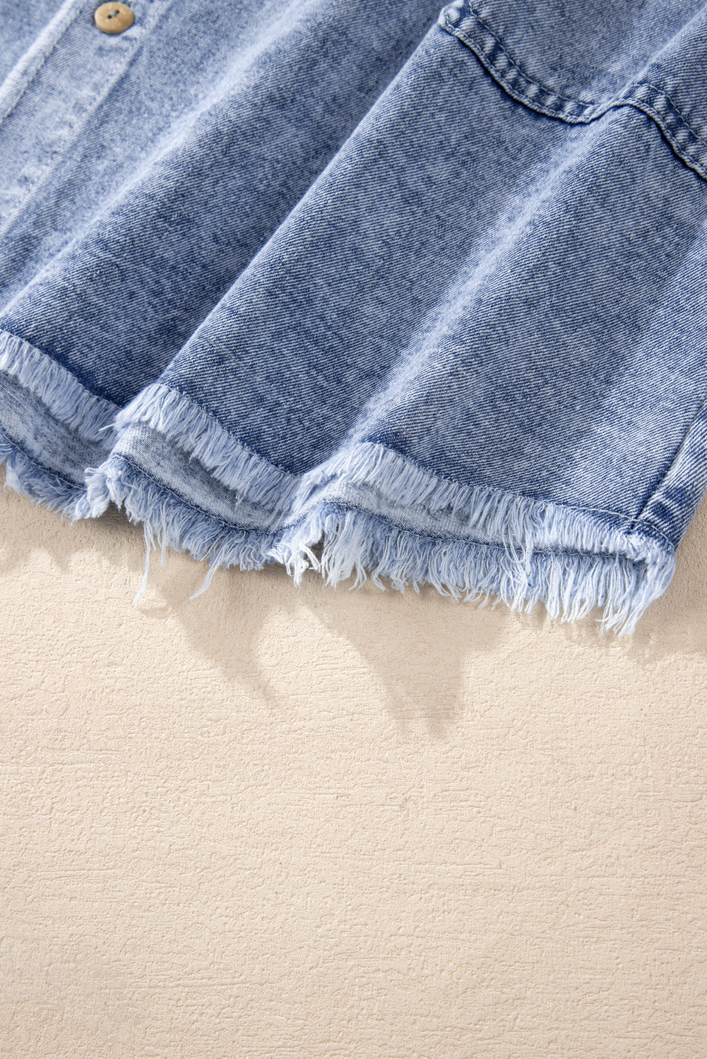 VYSN raw hem button-down long sleeve denim dress displayed on a hanger, showcasing its casual style and distressed hem detail.