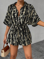 Striped button-up belted romper jumpsuit by Trendsi, featuring long sleeves and a stylish waist tie, displayed on a hanger.