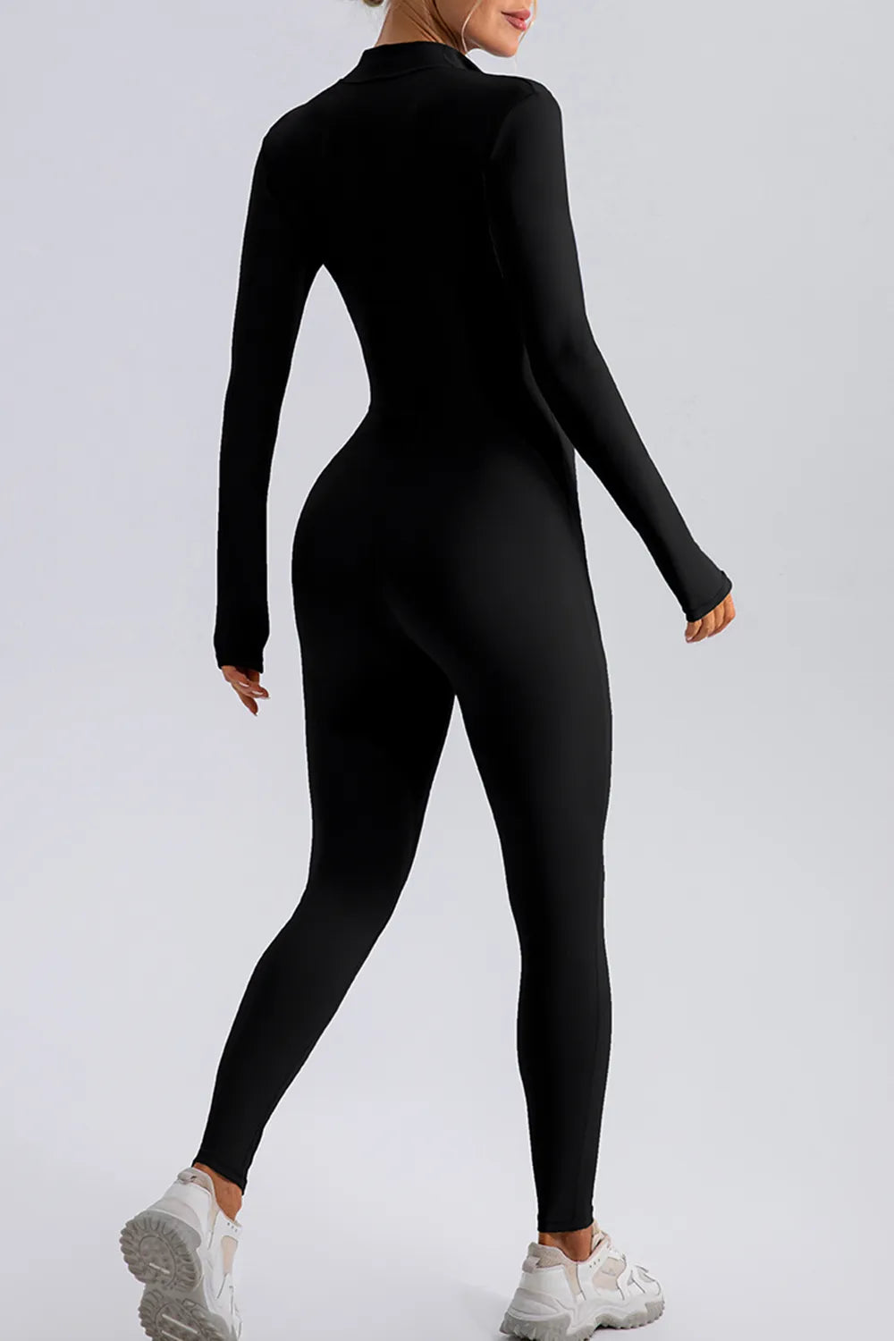 Trendsi half zip mock neck active jumpsuit in black, form-fitting athletic wear with long sleeves and a sleek design.