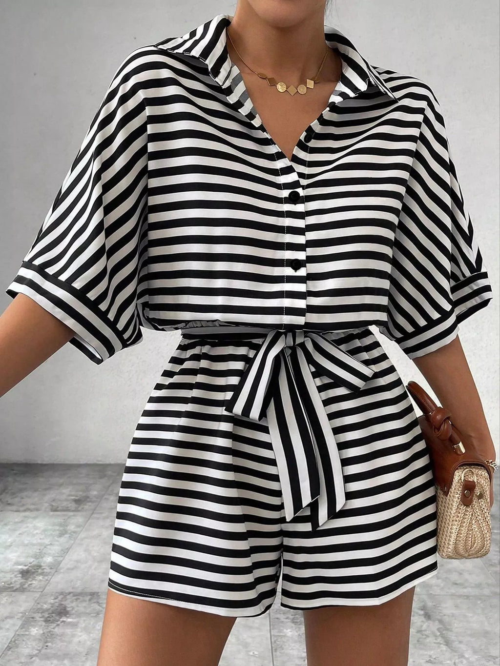 Striped button-up belted romper jumpsuit by Trendsi, featuring a casual design with vertical stripes and a comfortable fit.