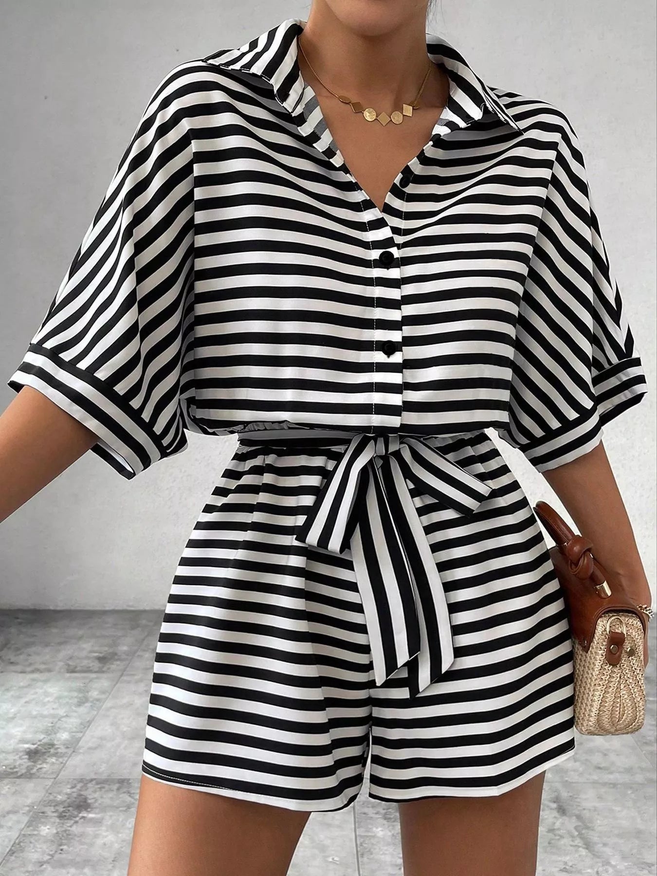 Striped button-up belted romper jumpsuit by Trendsi, featuring a casual design with vertical stripes and a comfortable fit.