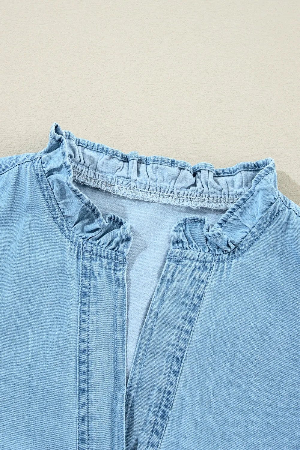 VYSN button-up notched long sleeve denim dress hanging on a wooden hanger, showcasing classic denim style and tailored fit.