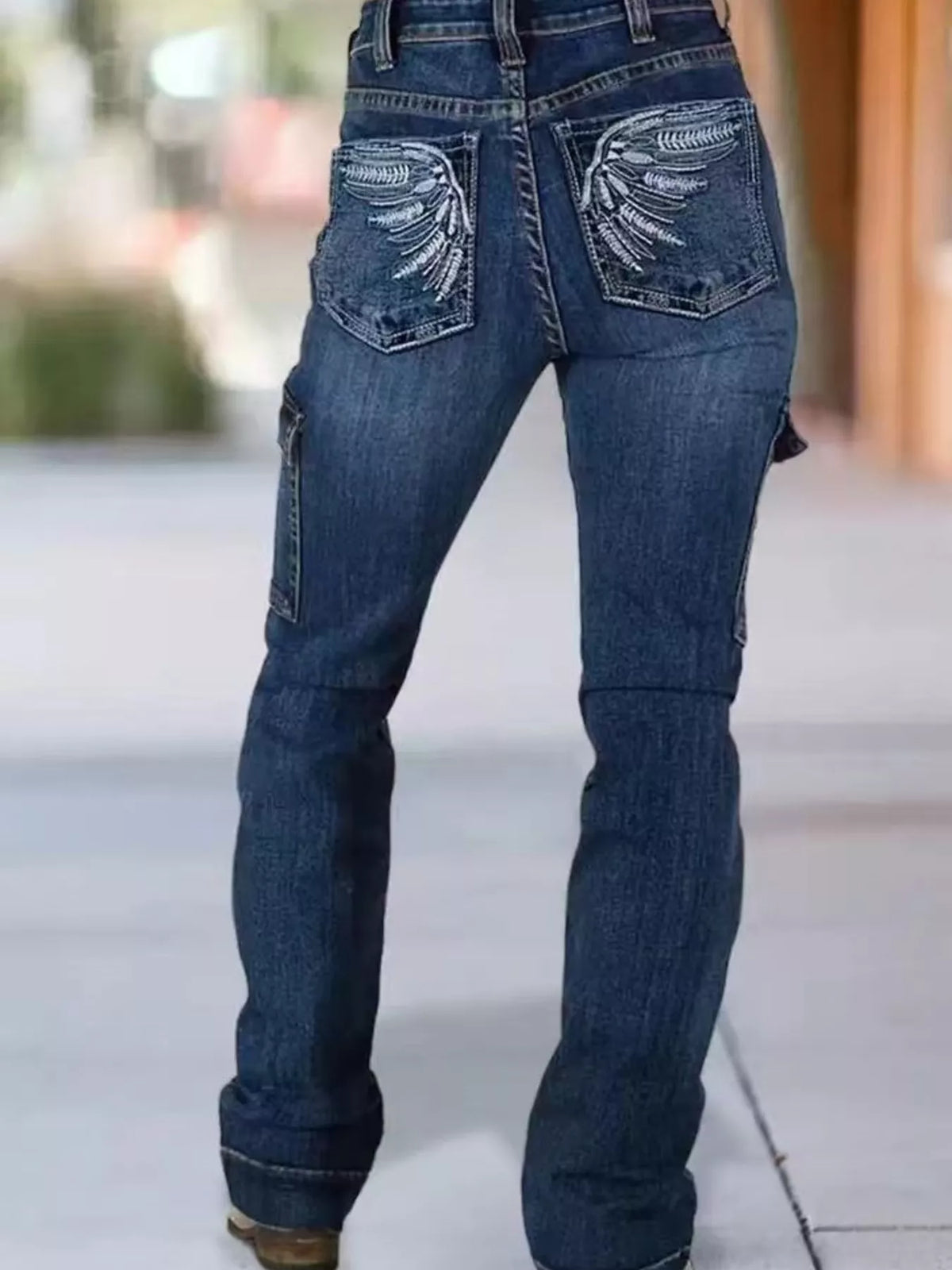 Wings embroidered high-rise cargo jeans from Trendsi showing front view with embroidered wing details and multiple cargo pockets.