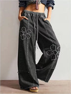 Wide-leg jeans with floral appliqué details from Shopimist, featuring a relaxed fit and decorative floral embroidery on the denim.
