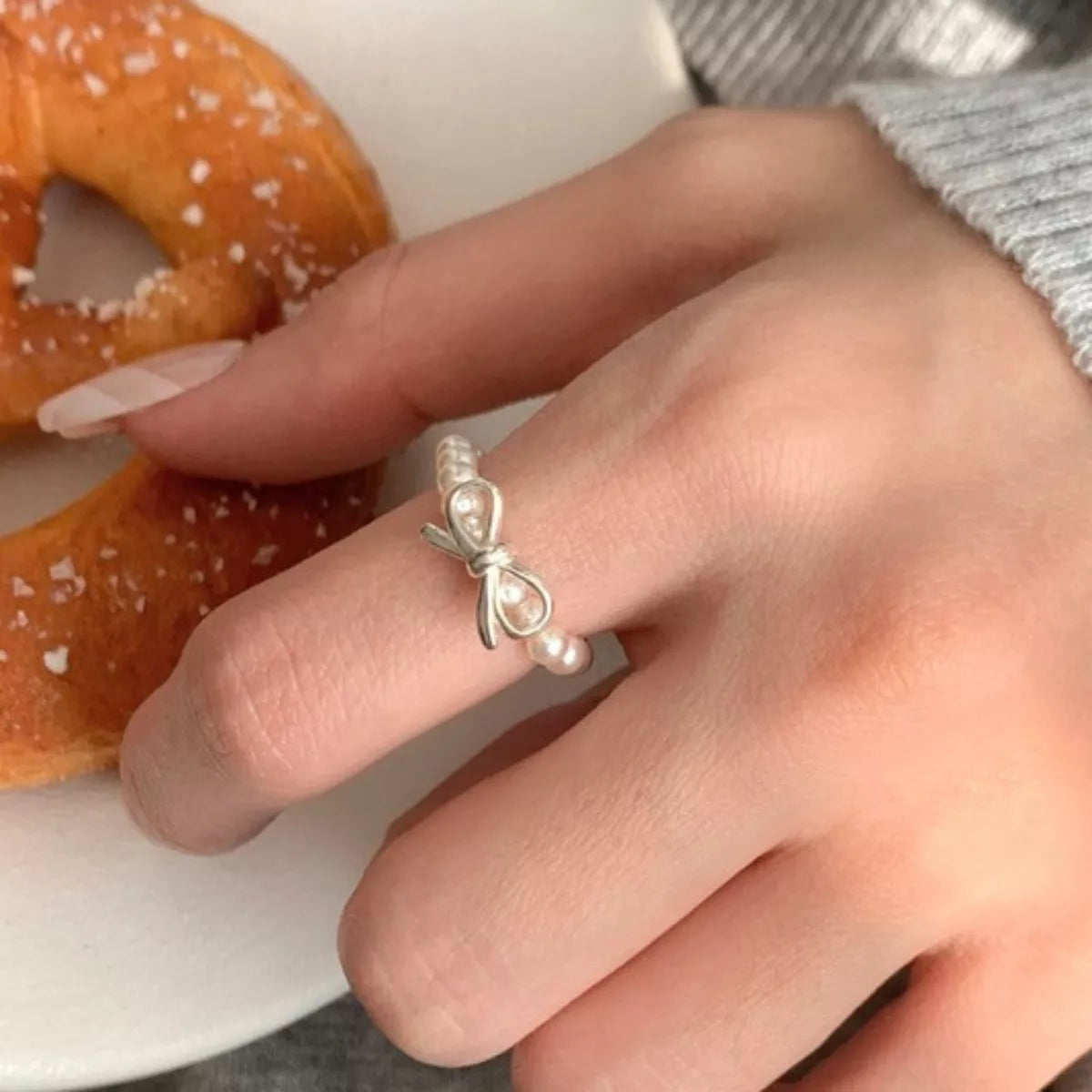 Shopimist Bow Pearl Beaded Ring featuring a delicate bow design with pearl accents on a sleek metal band.