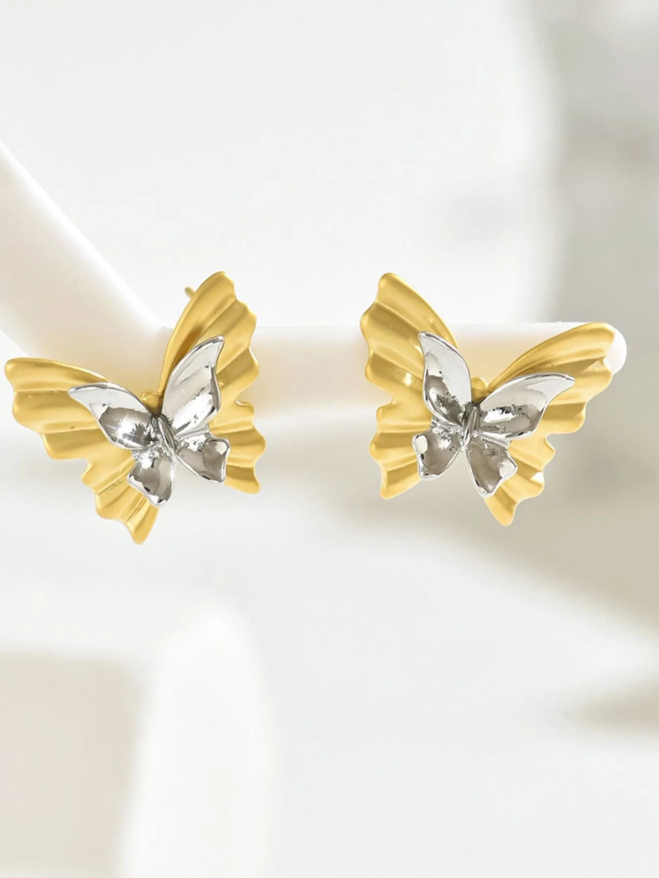 Two-tone stainless steel butterfly earrings with intricate wing design, stylish jewelry accessory for pierced ears.